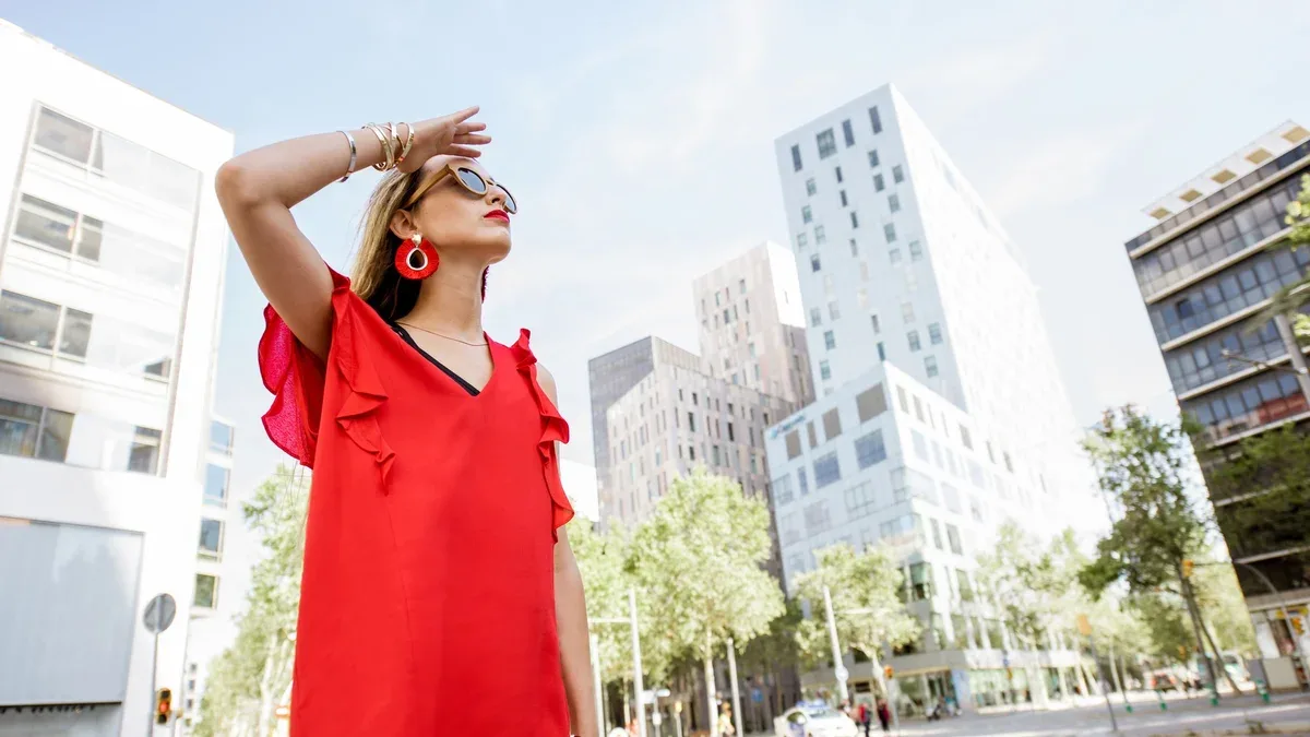 Portrait de mode de vie d'une femme en robe rouge debout à l'extérieur dans le quartier des affaires moderne de la ville de Barcelone