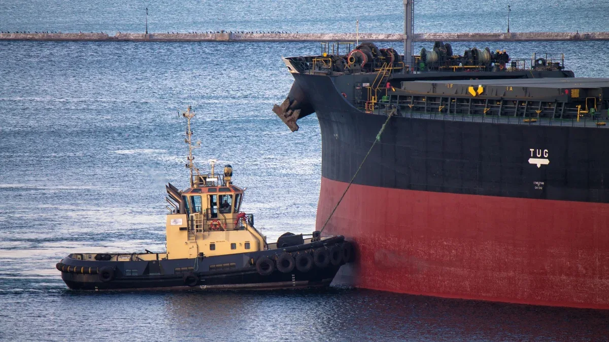 Amarrage des navires au port avec assistance de remorqueur sur corde d'amarrage avec brise-lames en arrière-plan