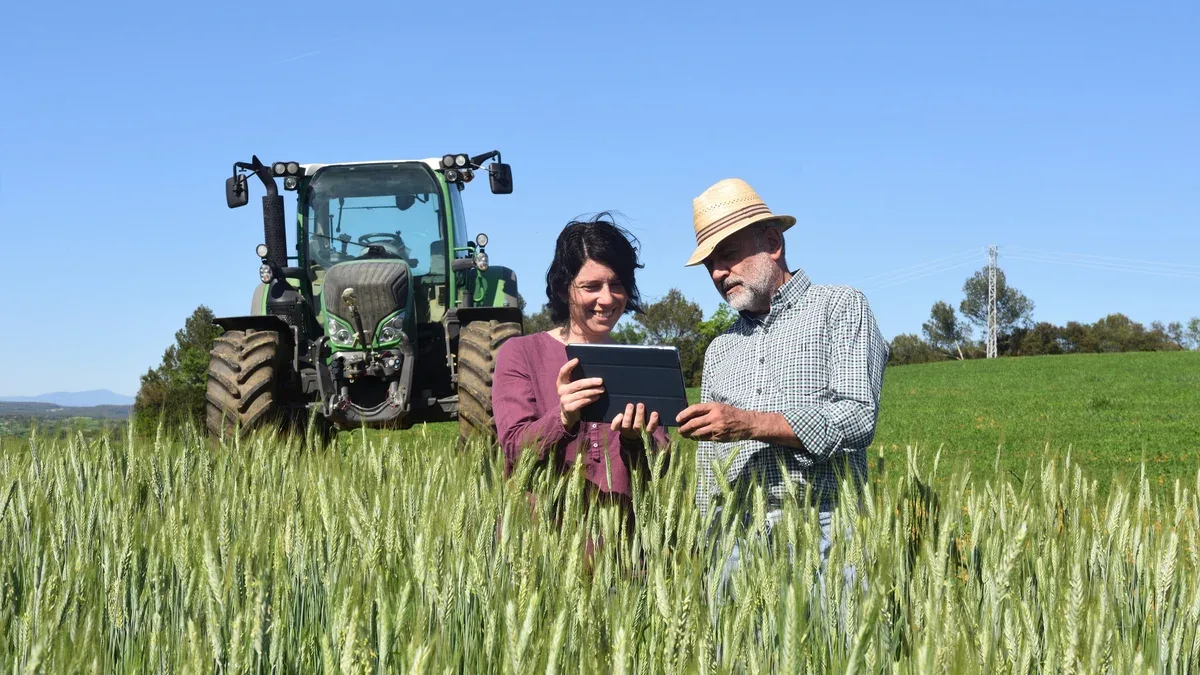 Couple d'agriculteurs dans un champ avec une tablette numérique
