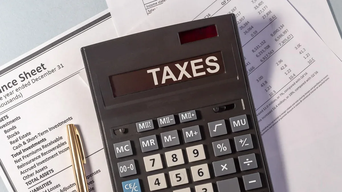 Mot TAXES sur l'affichage de la calculatrice sur les documents papiers et le stylo doré
