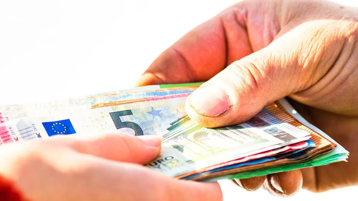 Gros plan d'une main tenant du papier sur fond blanc