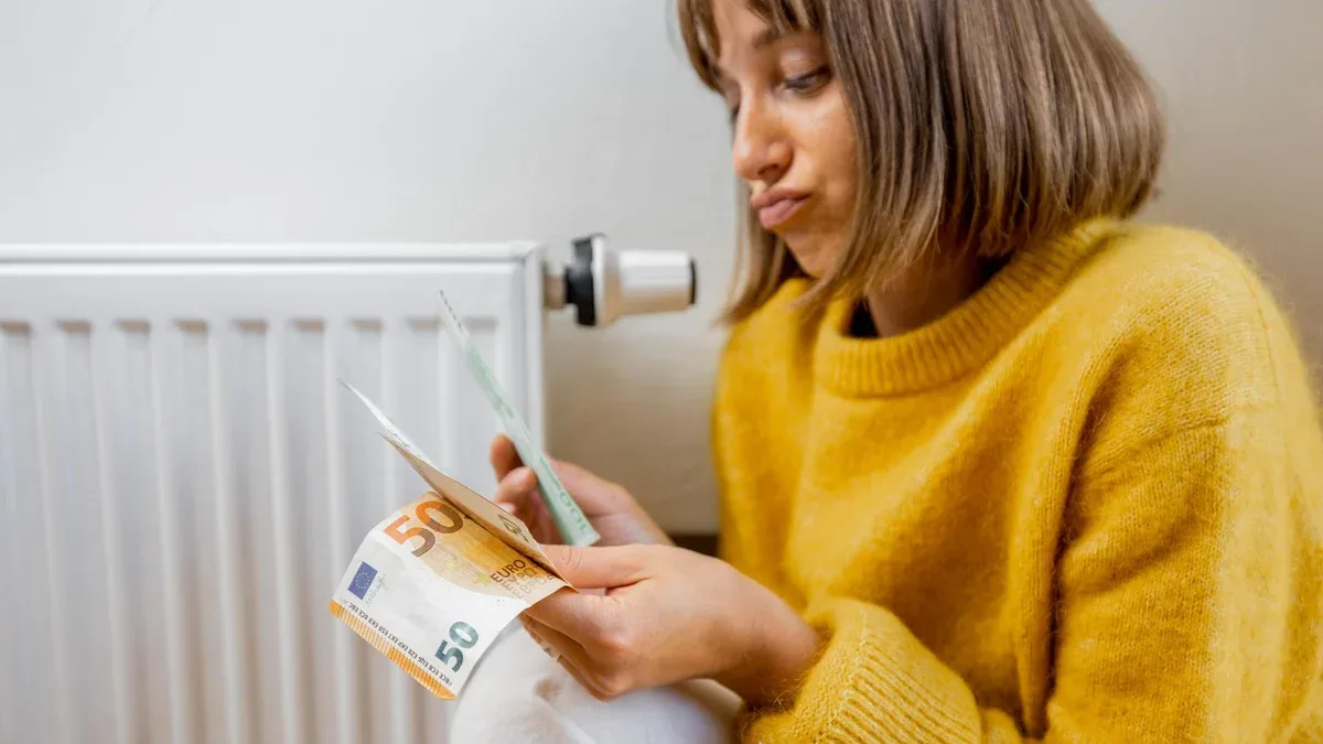 Femme chaudement habillée comptant de l'argent près du radiateur