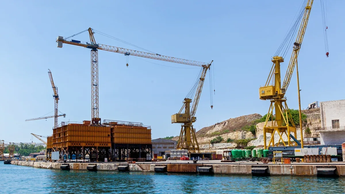 Une grue colorée est placée sur un quai flottant dans le port, à Malte. Seascape avec vue sur la technique industrielle.